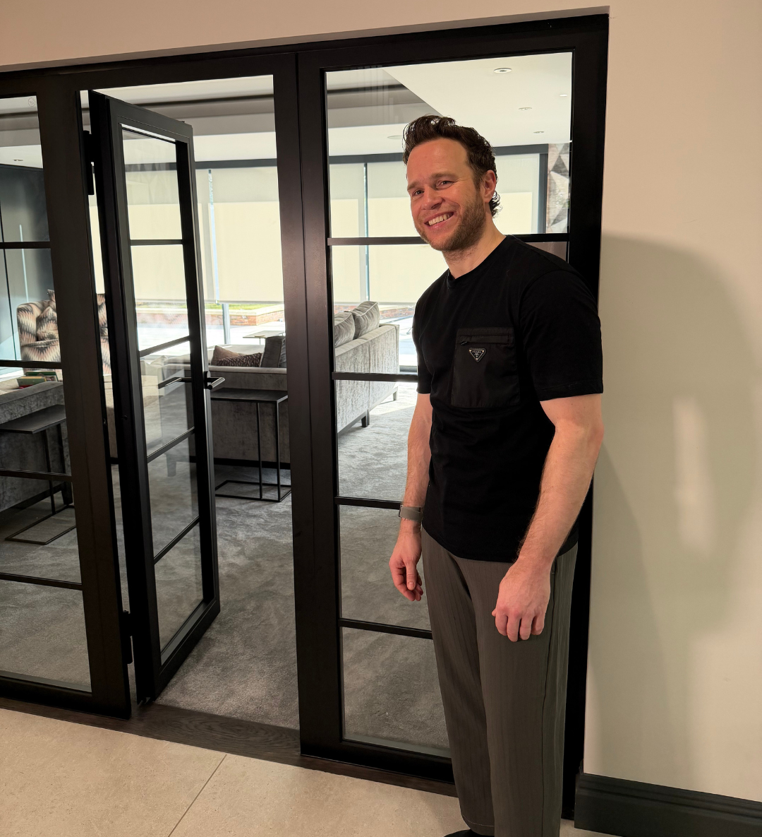 Olly Murs standing beside a black fire-rated steel door by Steel Door Company
