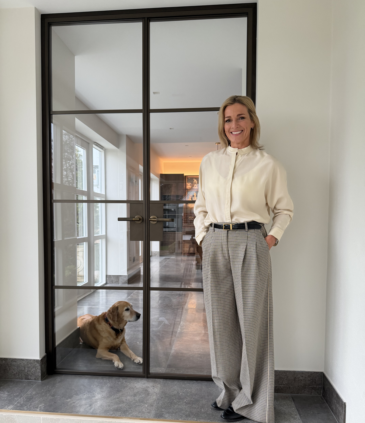 Gabby Logan standing in a modern interior setting with a dog by a Steel Door Company door.