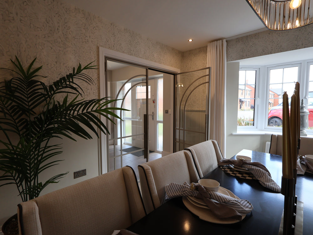 Double steel door with arched bars and hammered pull handles in Ivory Sands finish in a dining room