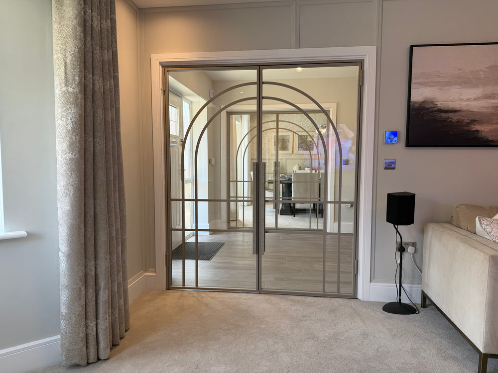 Double steel door with arched bars and hammered pull handles in Ivory Sands finish in a living room