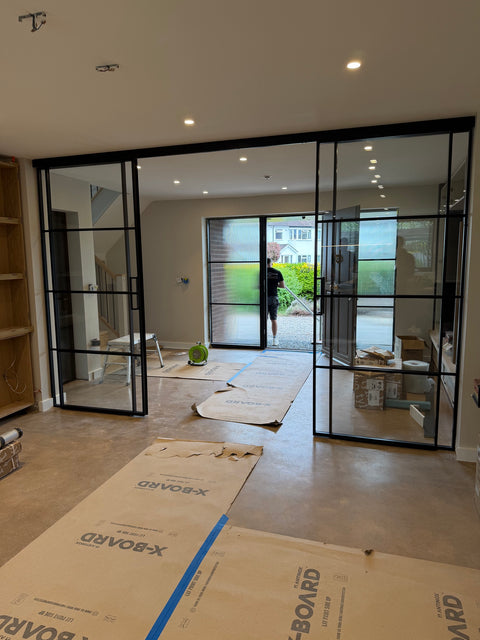 Living room with large glass doors and floor protection covering the floor.