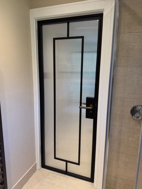 Internal single steel door with fluted glass installed in a toilet, offering additional privacy while still allowing natural light to flow through the space. Slim black steel frames create a clean, modern finish suited to contemporary interiors.
