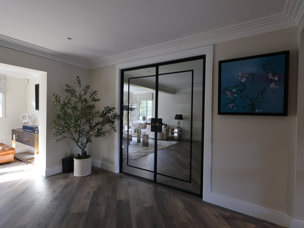 Modern interior with a glass door, plant, and artwork on a wall.