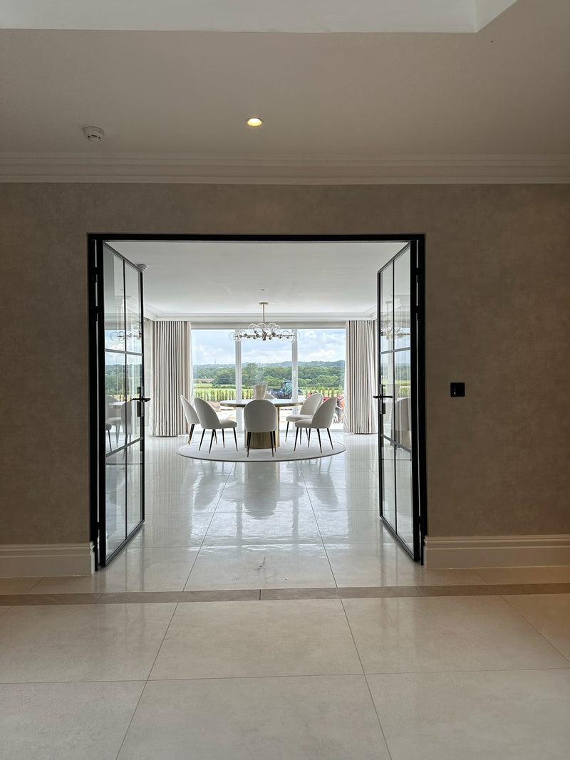 Modern interior with open glass doors leading to a dining area with a table and chairs.