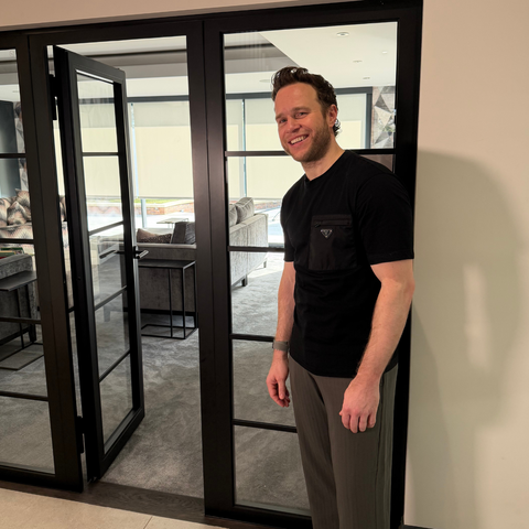 Olly Murs standing by his living room fire door