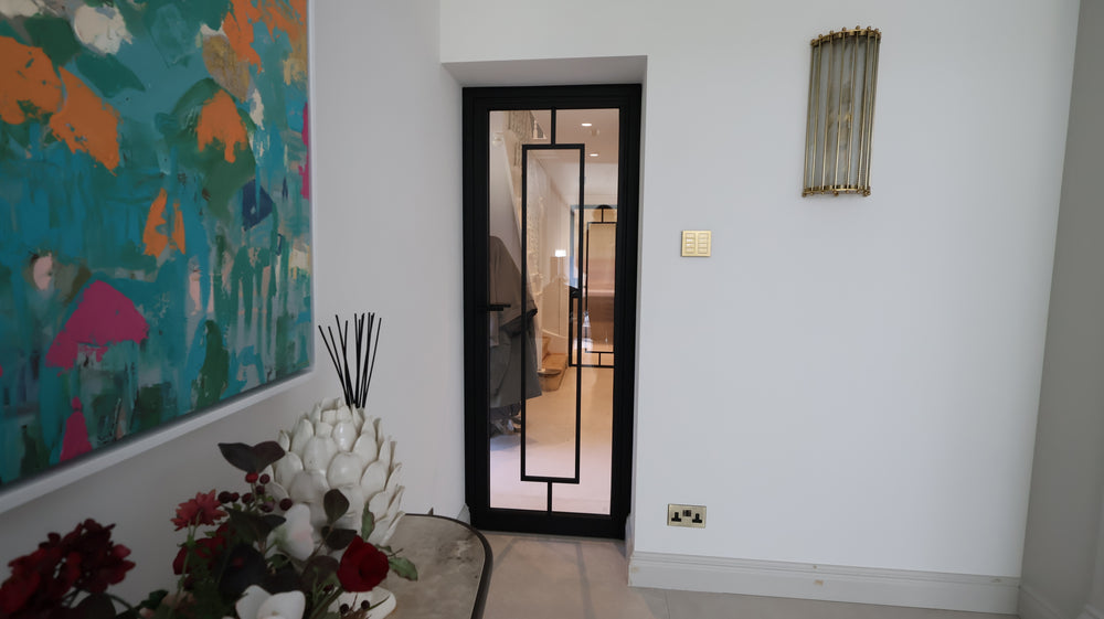 Black FD30 fire-rated steel door with slim sightlines and clear glazing connecting contemporary interior spaces.