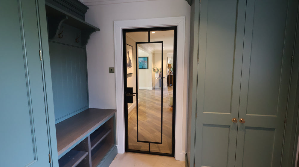 Black steel framed internal door with slim sightlines connecting a bespoke boot room to open-plan living spaces