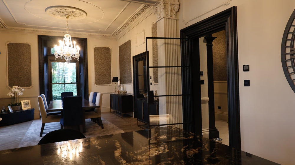 Dining room with a chandelier, chairs, and a large open steel door leading to another room.